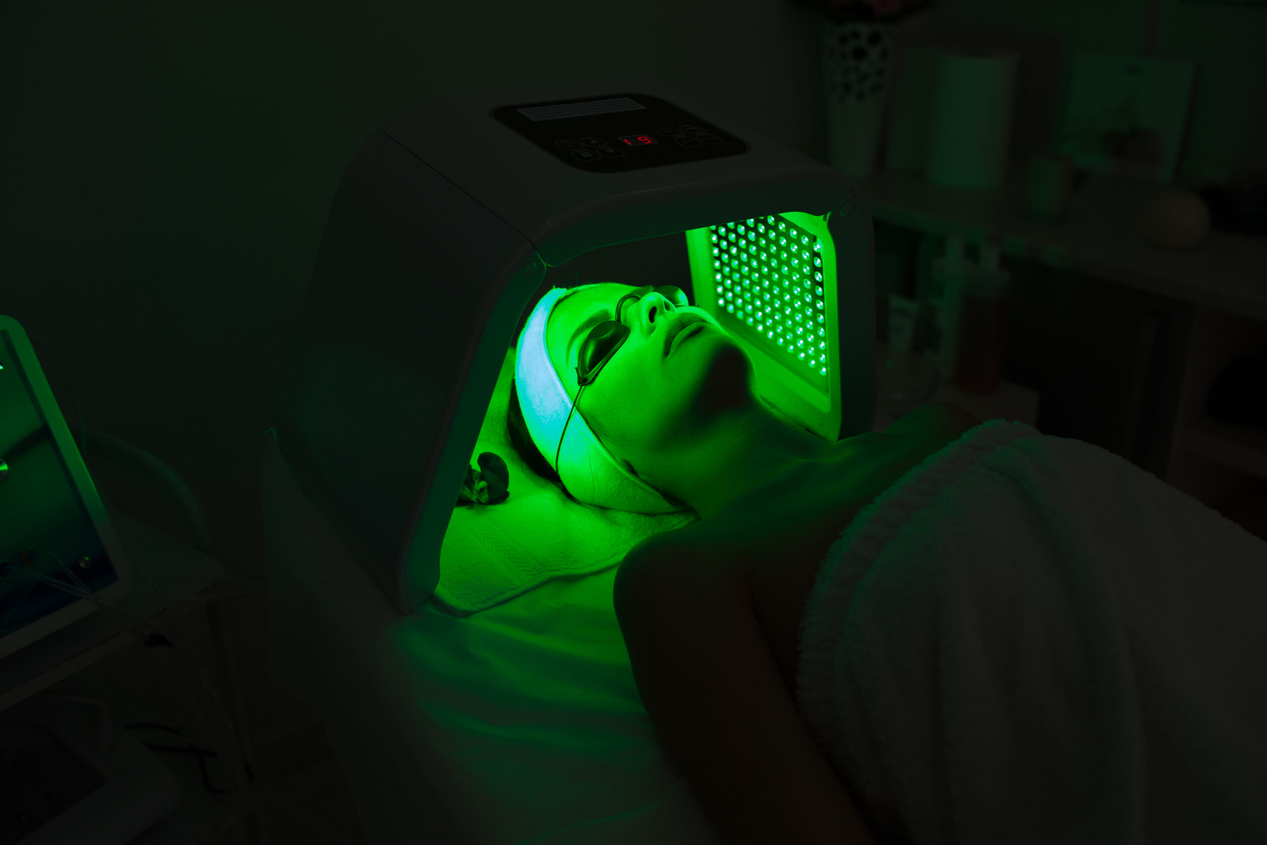 Woman having Ultraviolet LED light facial treatment at beauty salon.